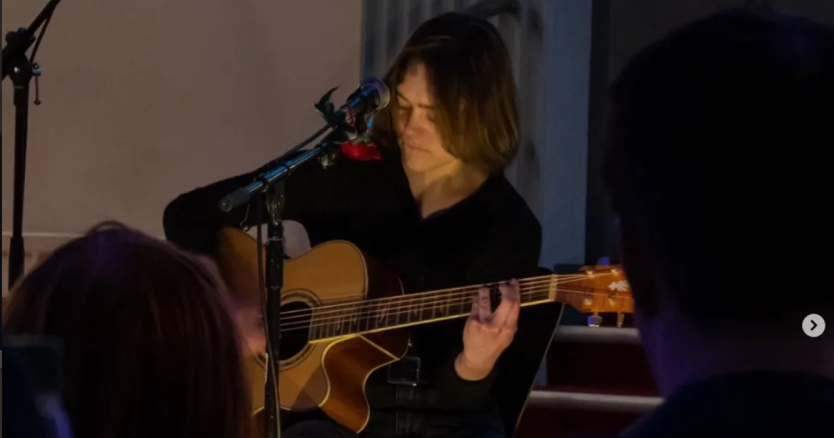 Han Nelson playing acoustic guitar during a live performance